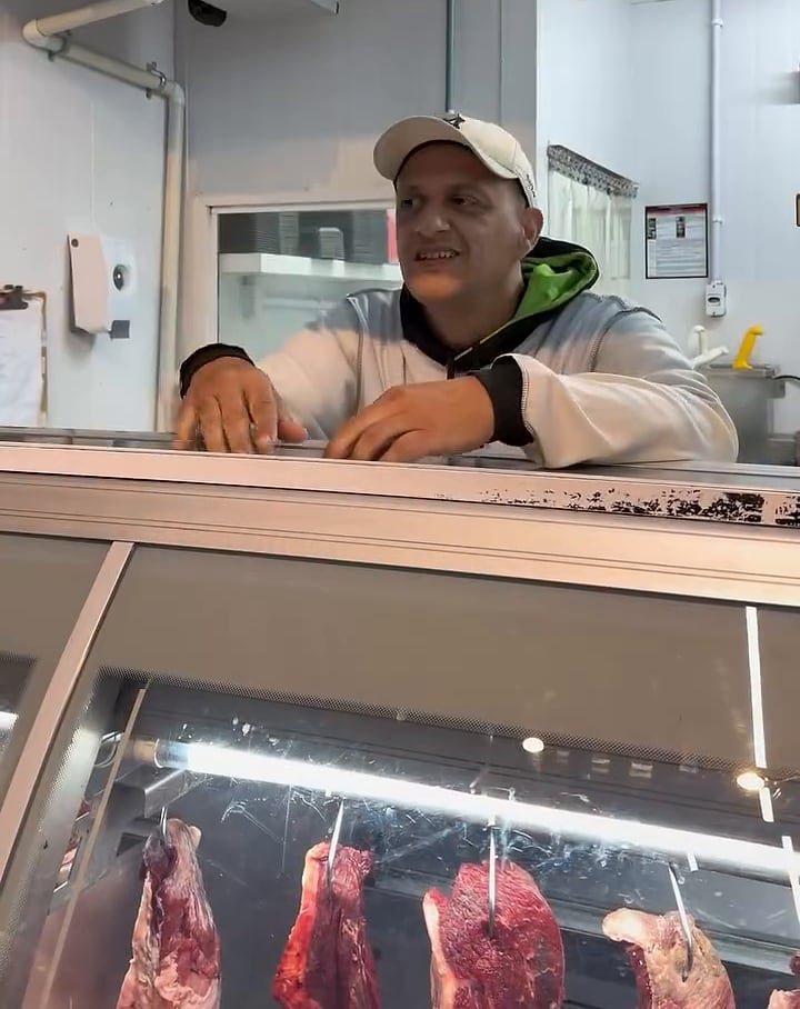 Açougueiro da TIELI atrás do balcão refrigerado de carnes
